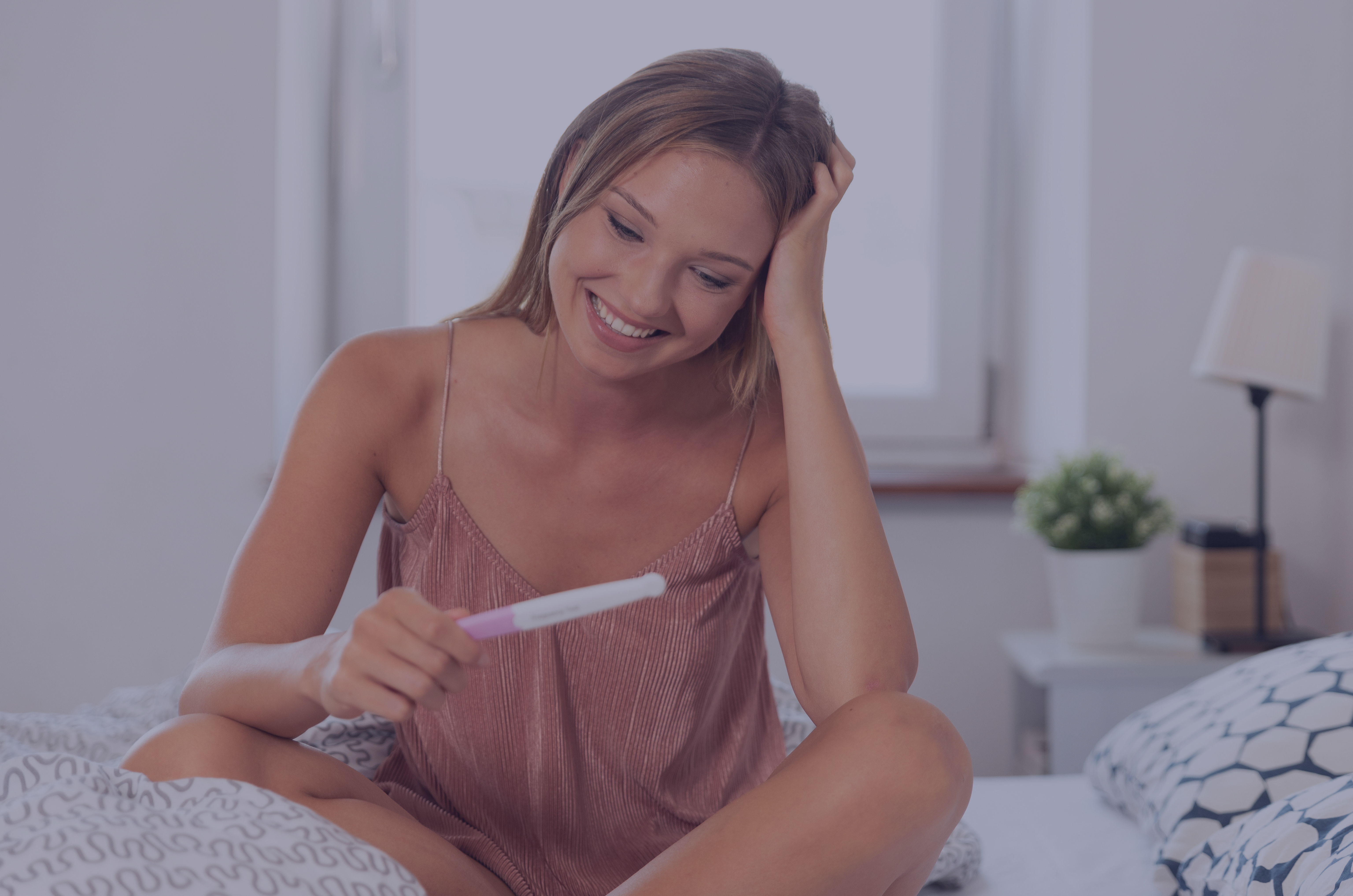 kobieta po transferze zarodka ciesząca się z pozytywnego wyniku testu ciążowego