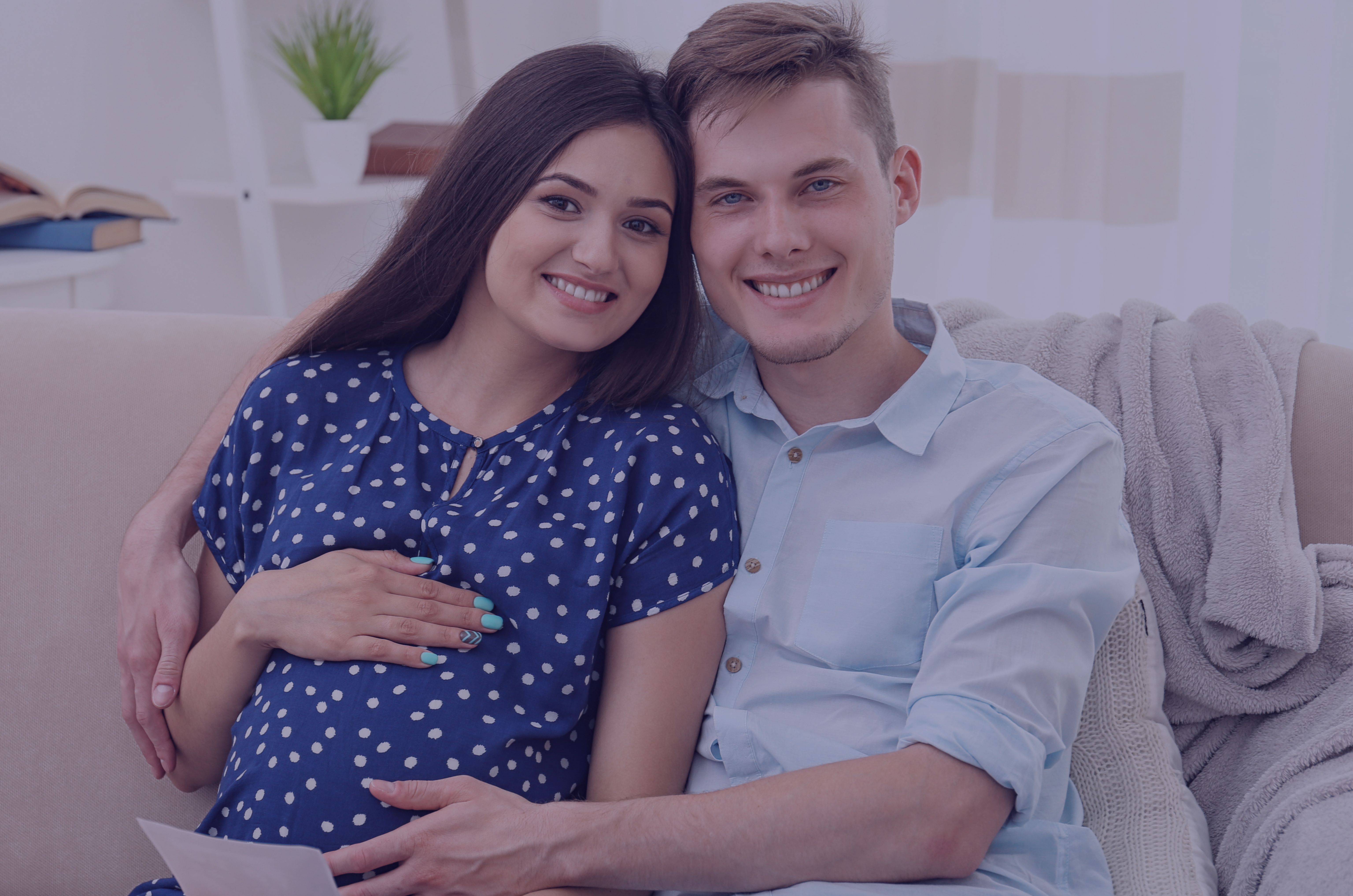 uśmiechnięta para w ciąży siedząca na kanapie